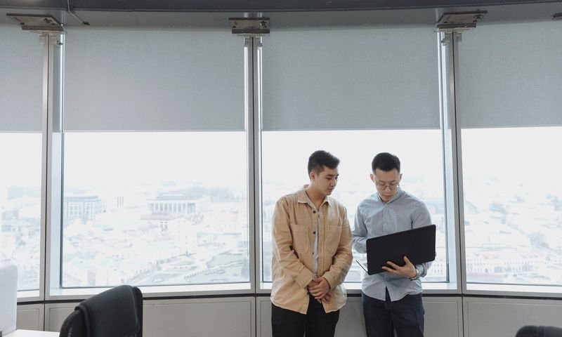 Two professionals discussing business strategy with a laptop in a modern office.