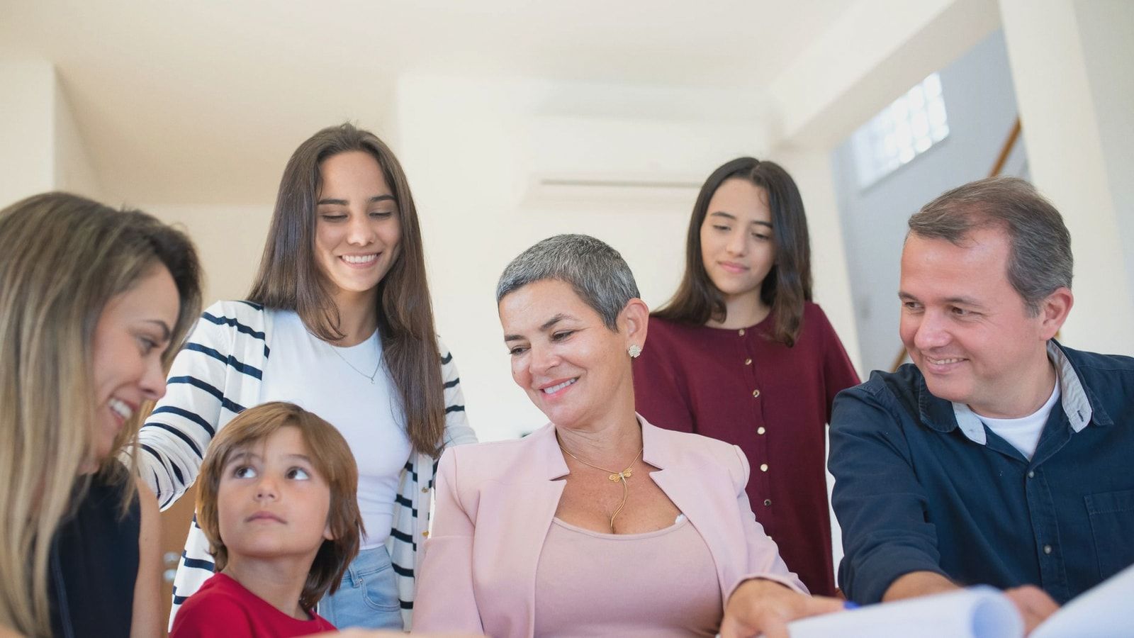 A family gathering around a table, discussing real estate documents indoors with a realtor.