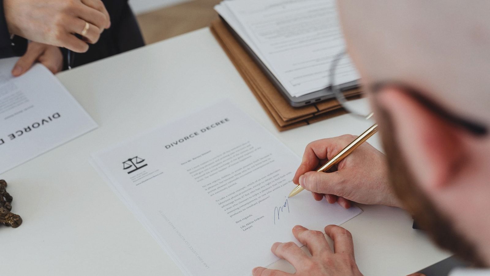 Close-up of a person signing a divorce decree on a desk.