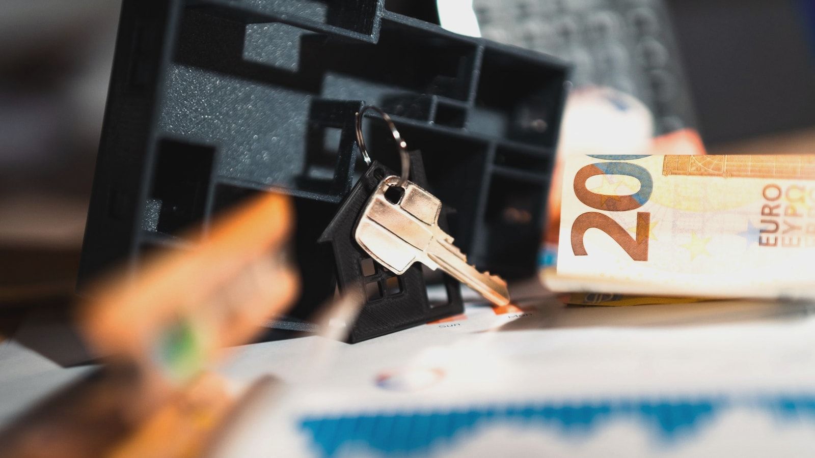 Keys with a house model, Euro bills, and charts suggesting real estate and financial themes.