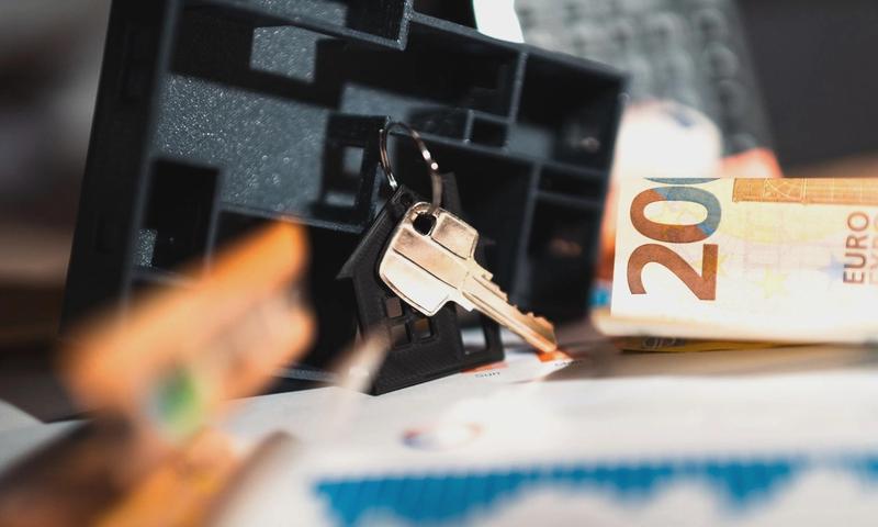 Keys with a house model, Euro bills, and charts suggesting real estate and financial themes.