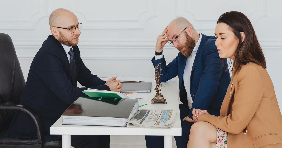 Lawyer consulting couple on divorce settlement in an office setting.
