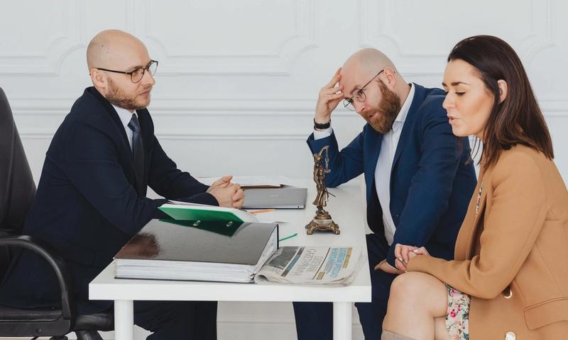 Lawyer consulting couple on divorce settlement in an office setting.