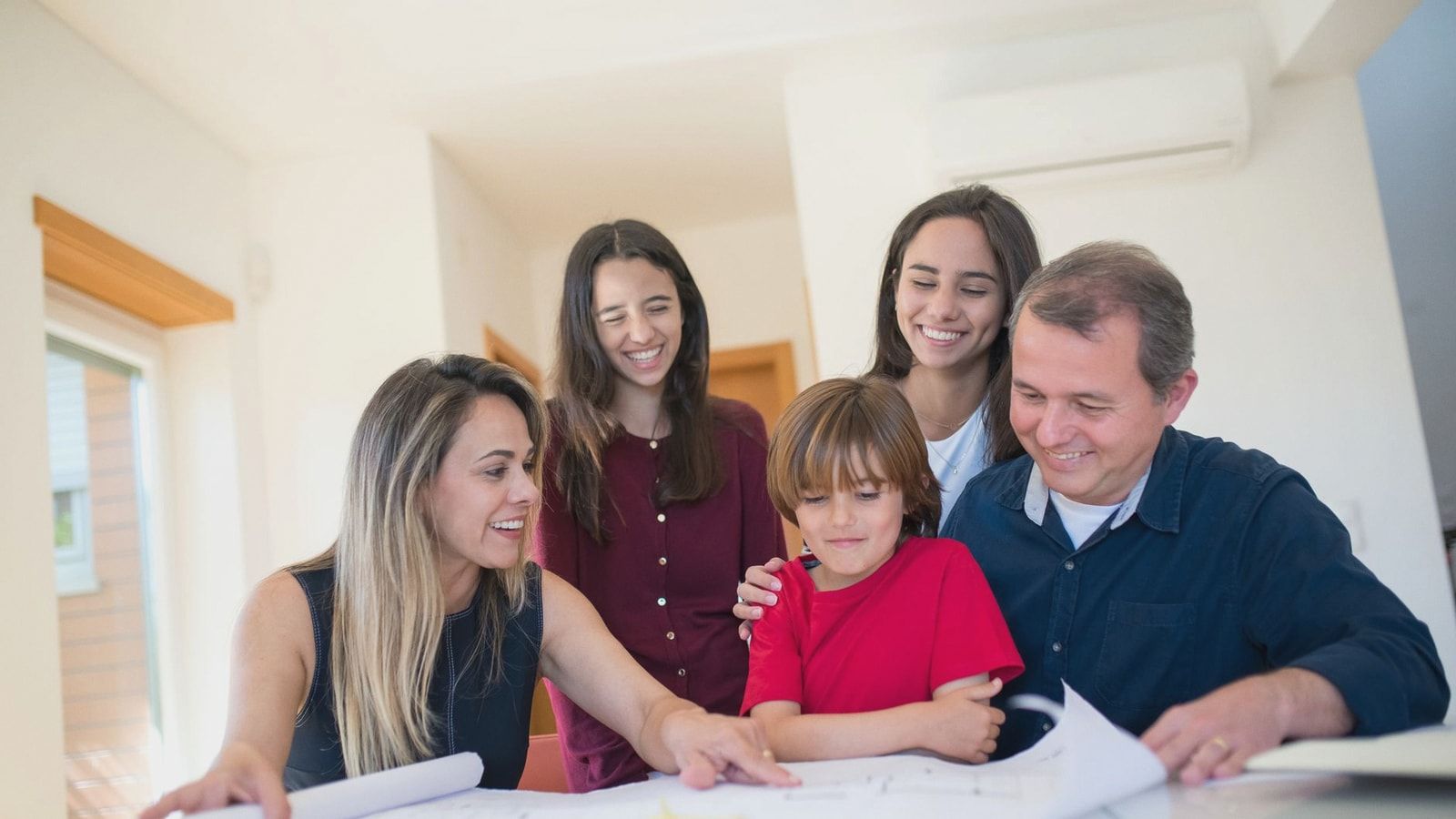 A joyful family gathered around a table reviewing a home blueprint together.