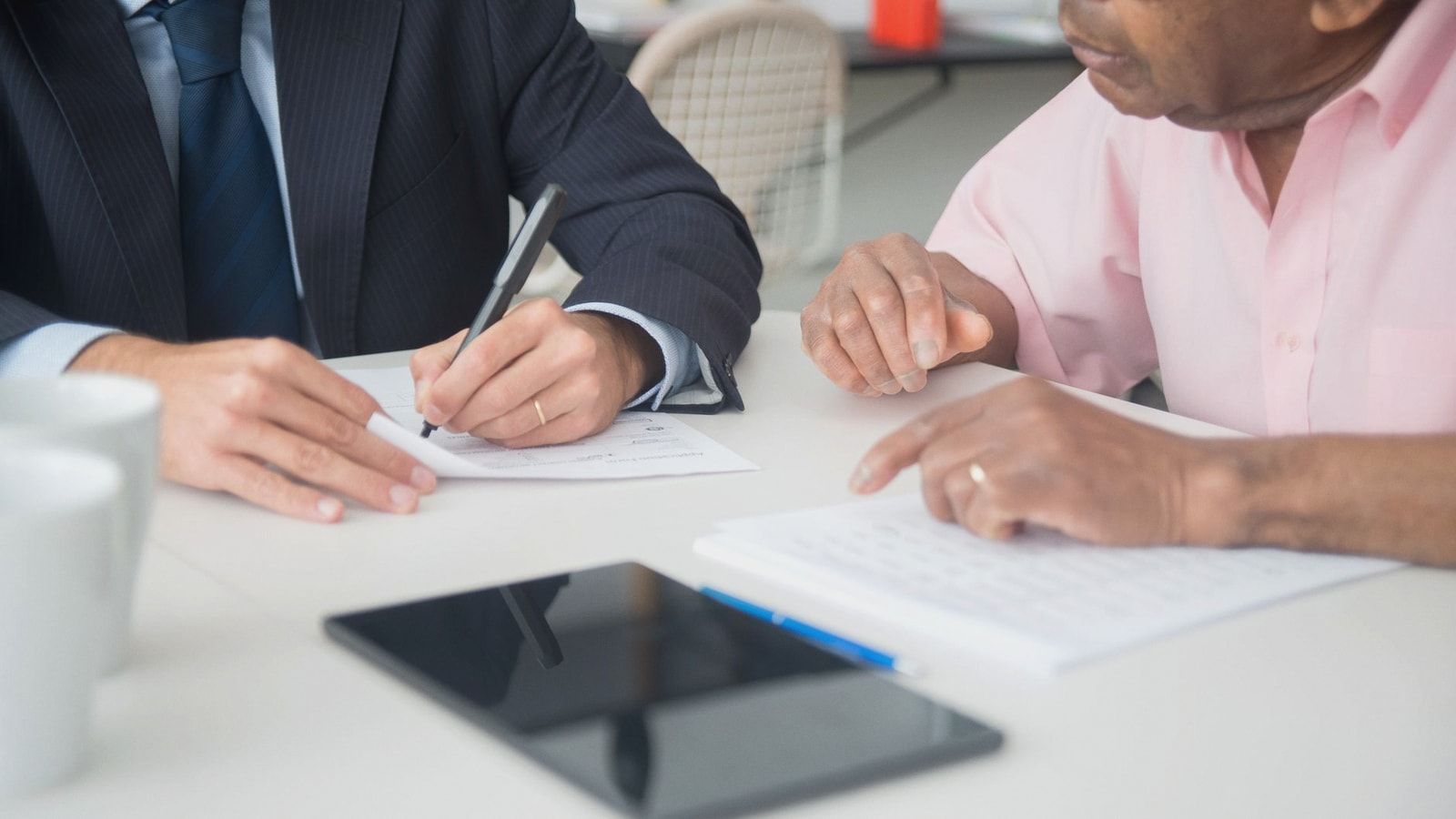 Two professionals discussing and signing documents in a business meeting.