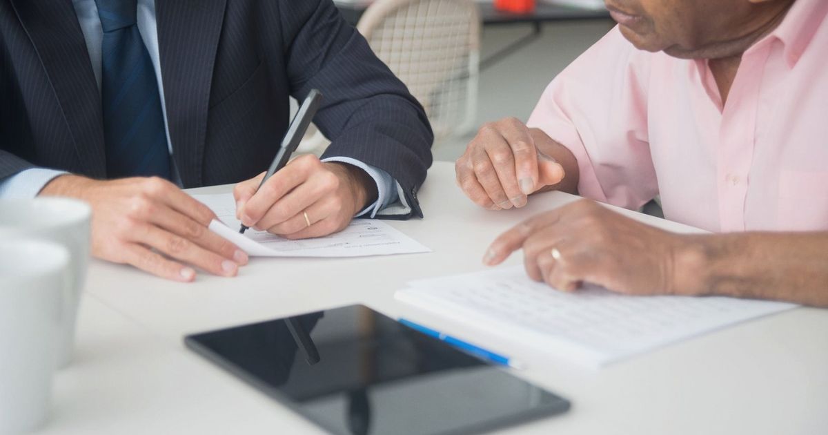 Two professionals discussing and signing documents in a business meeting.