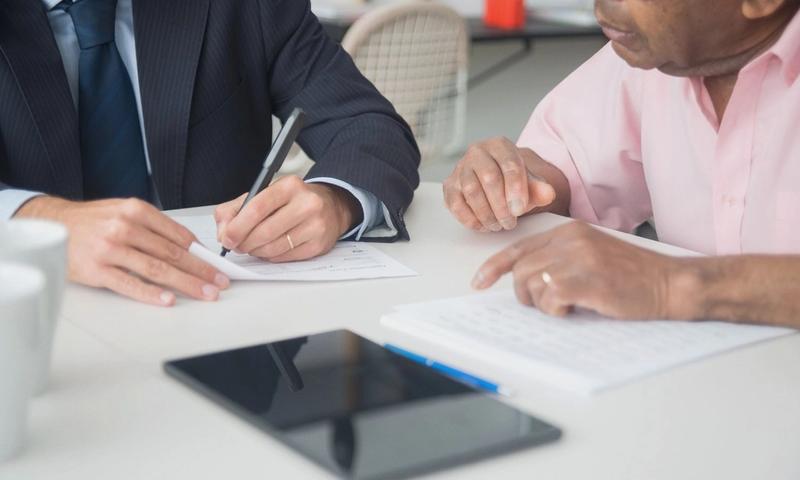 Two professionals discussing and signing documents in a business meeting.