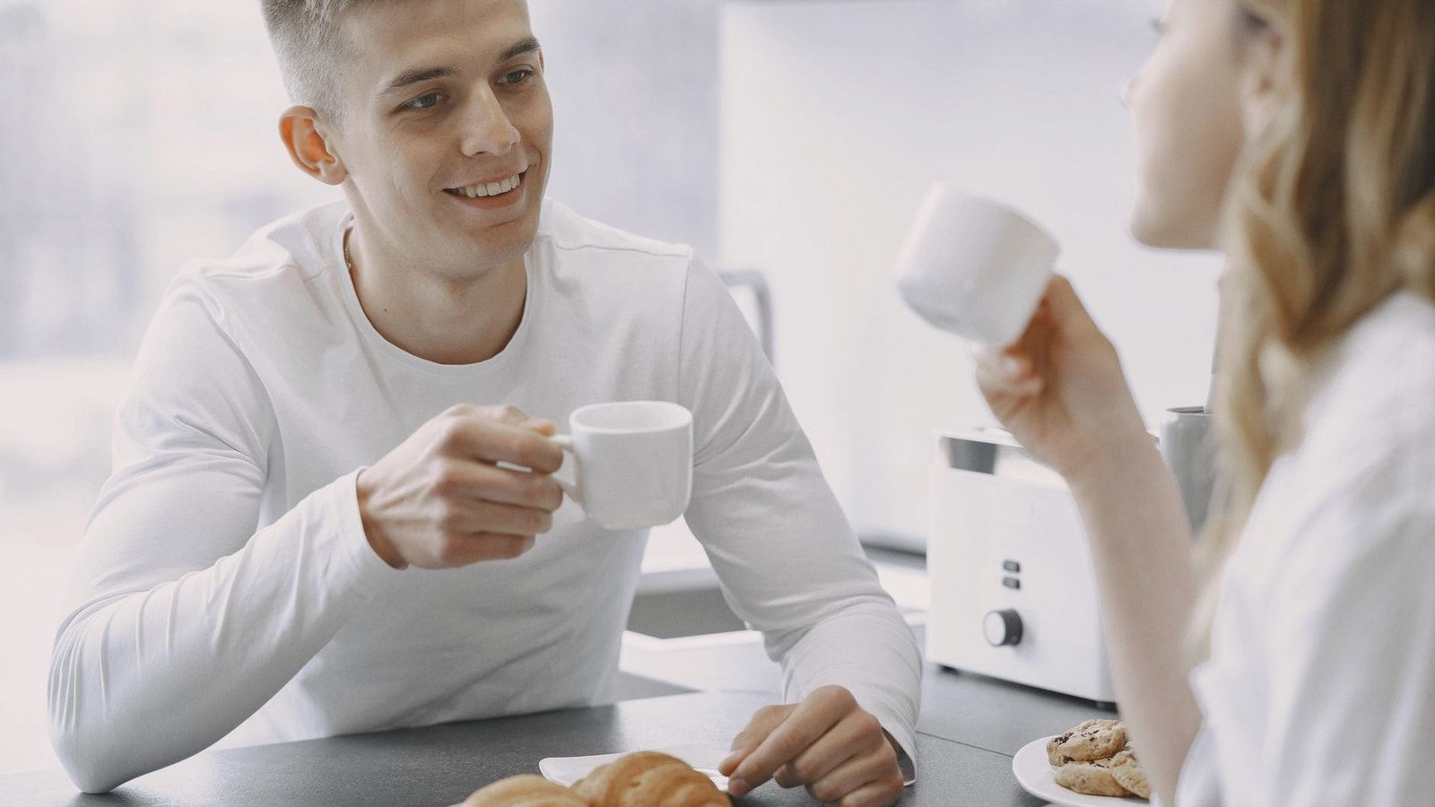 Smiling couple sharing a moment over coffee, highlighting warmth and connection.