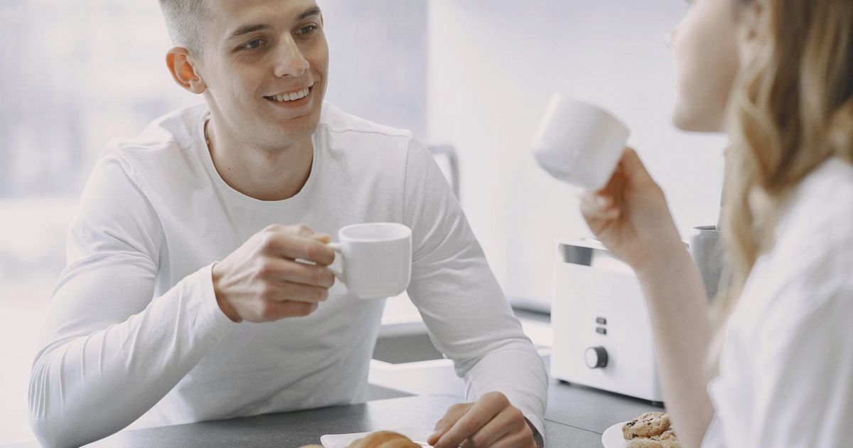 Smiling couple sharing a moment over coffee, highlighting warmth and connection.