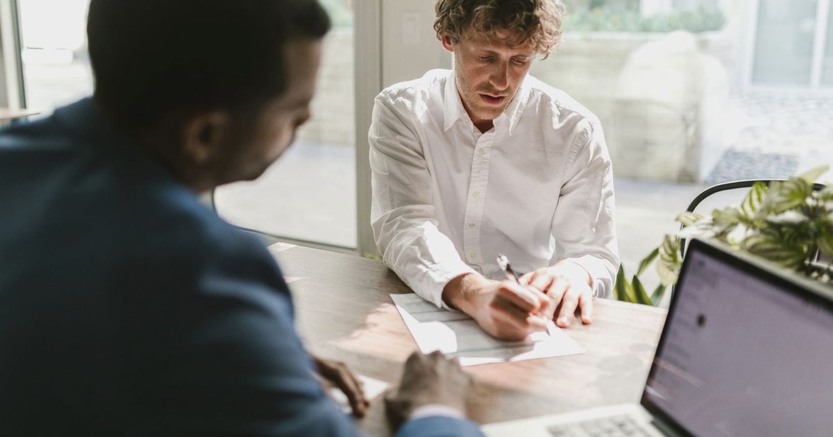 Two men collaborating in a modern office, reviewing and signing documents.