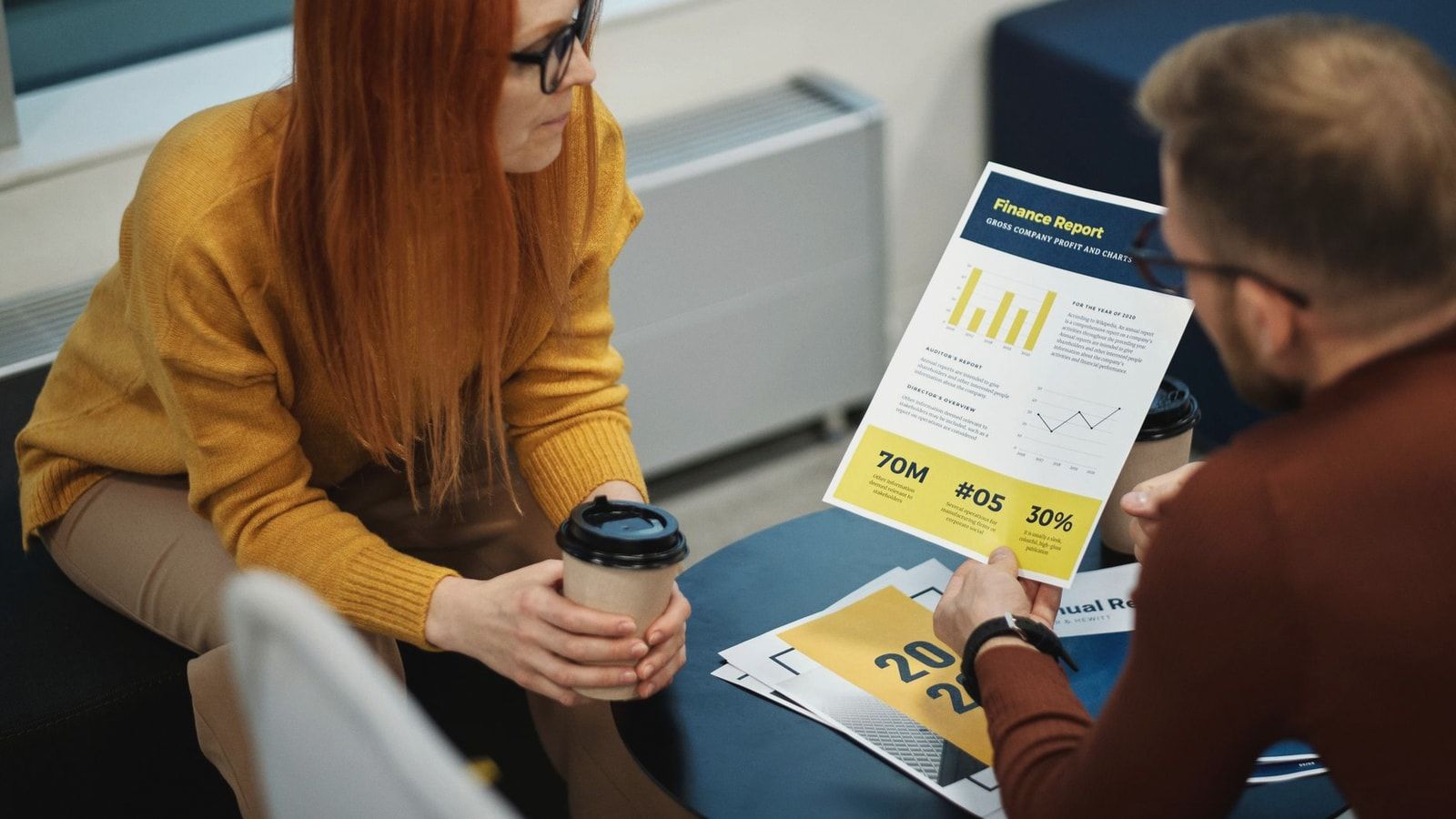 Two colleagues reviewing a financial report in a modern office setting.