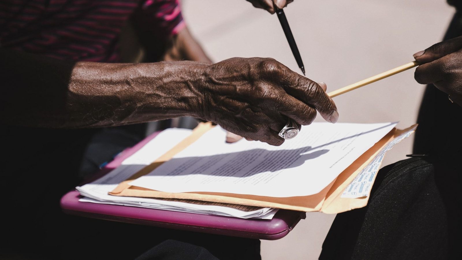 Close-up of hands exchanging documents with pens outdoors. Business agreement concept.