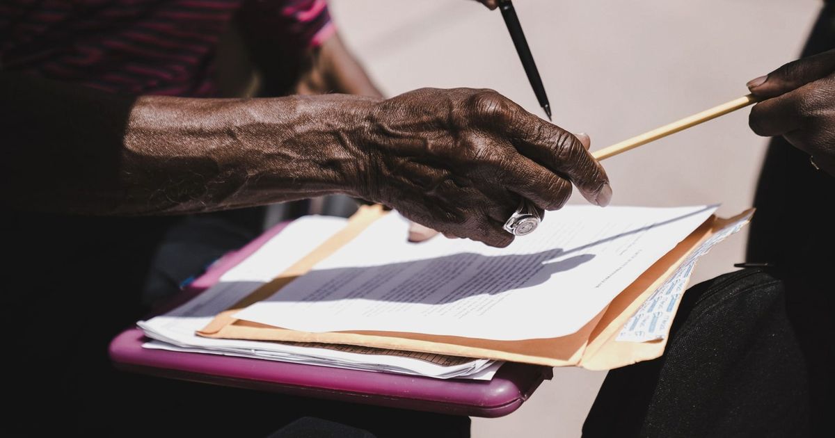 Close-up of hands exchanging documents with pens outdoors. Business agreement concept.