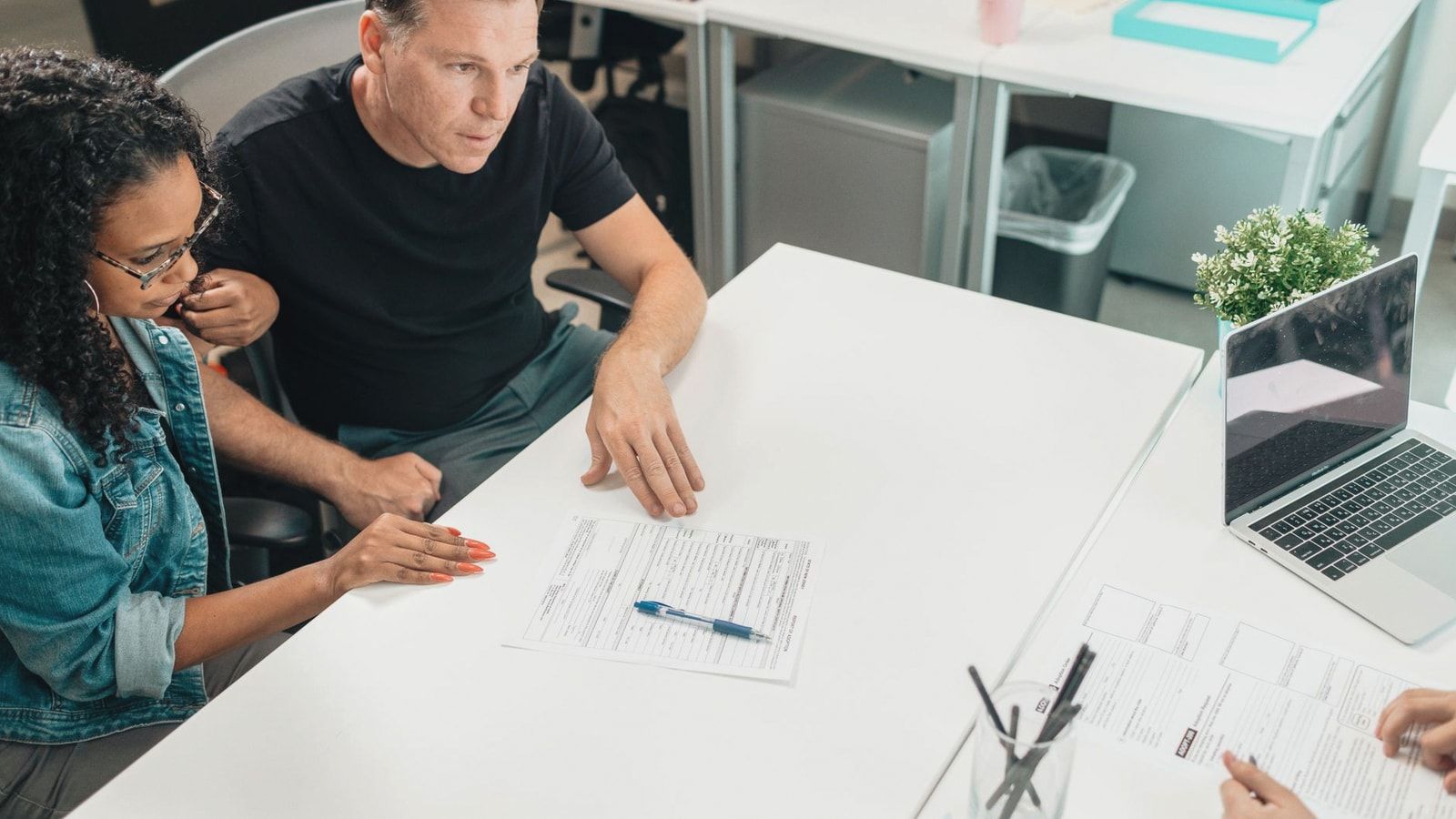 A couple discusses legal documents with a professional in a modern office setting.