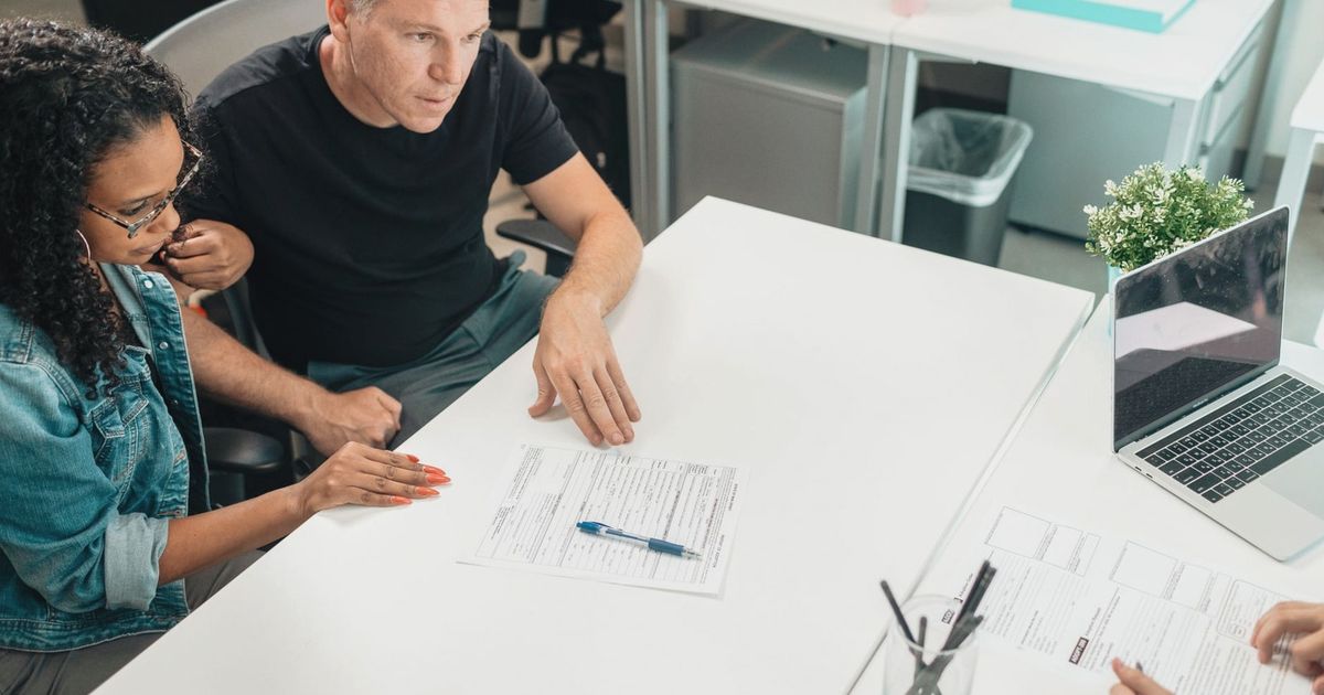 A couple discusses legal documents with a professional in a modern office setting.