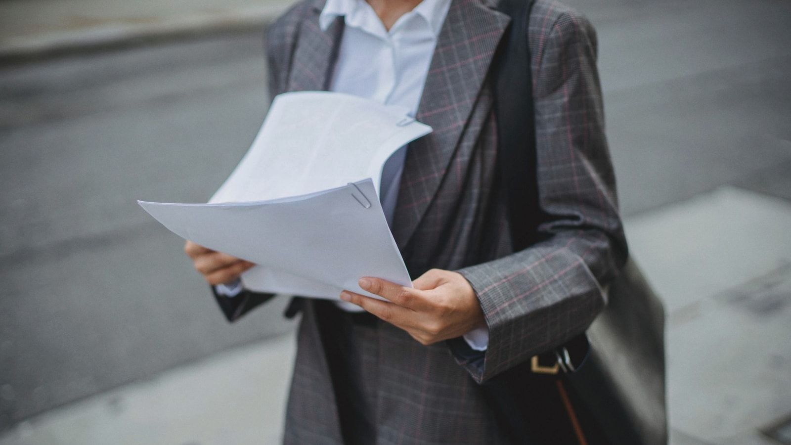 Professional businesswoman reviewing documents outdoors in a city environment.