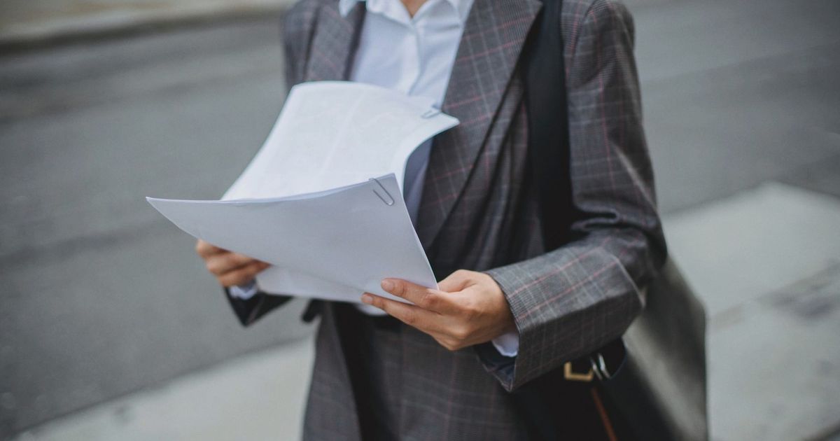 Professional businesswoman reviewing documents outdoors in a city environment.
