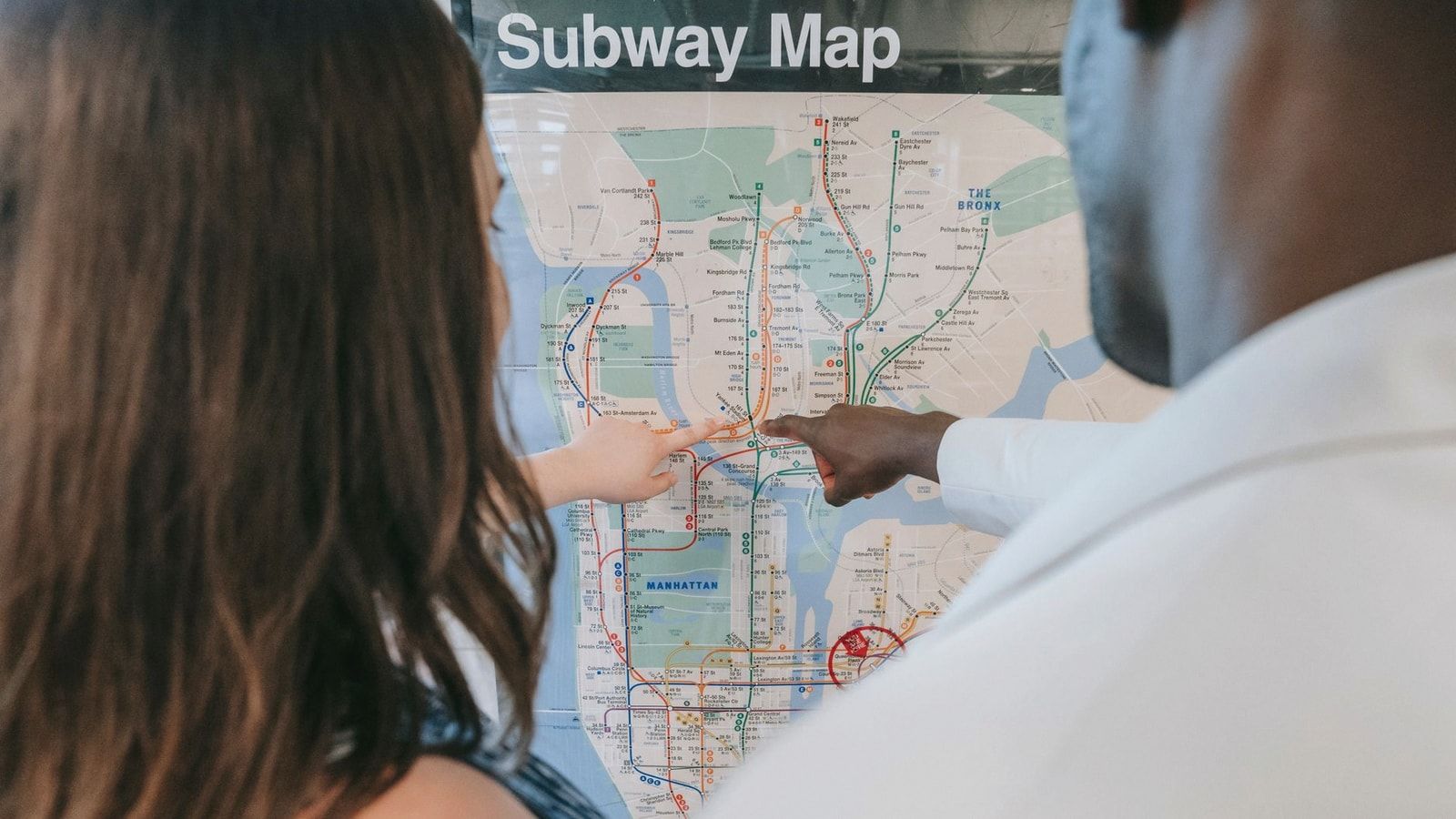 A couple examines a subway map, planning their route at a station.