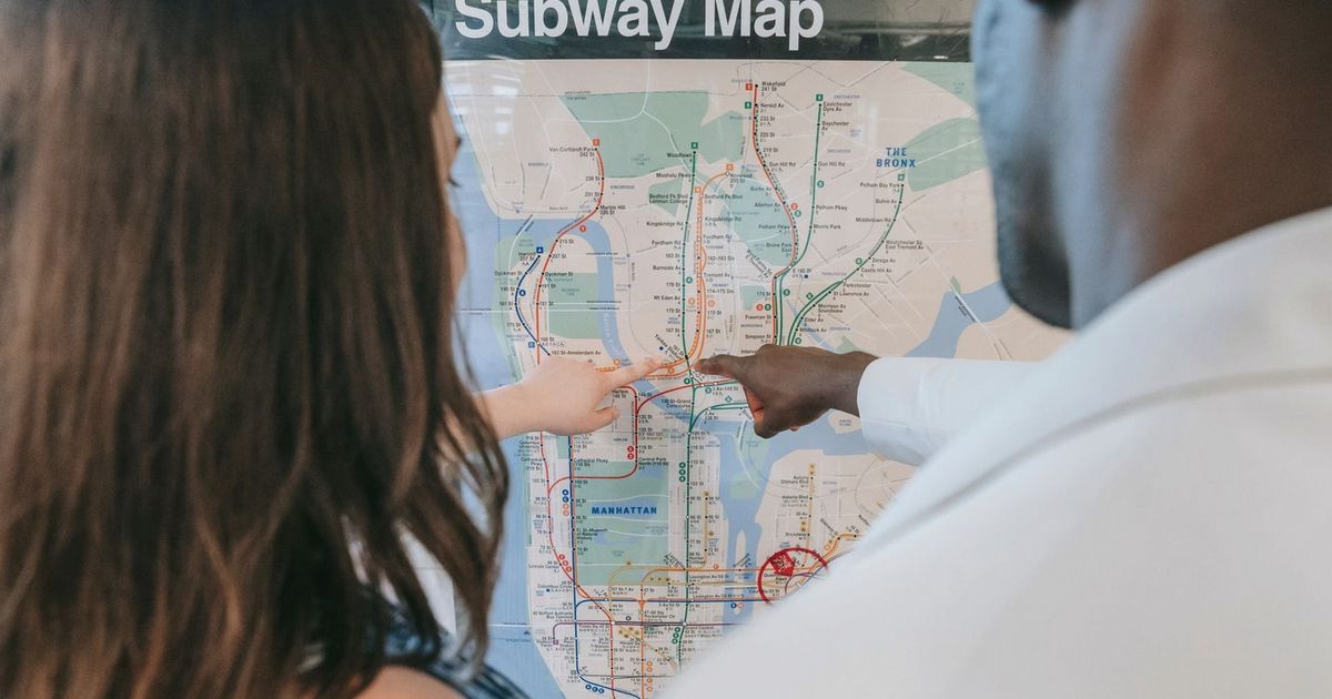 A couple examines a subway map, planning their route at a station.