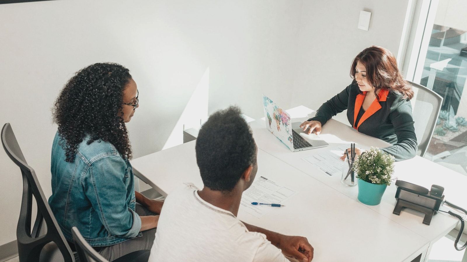 Diverse professionals having a business meeting indoors around a table with a laptop and documents.