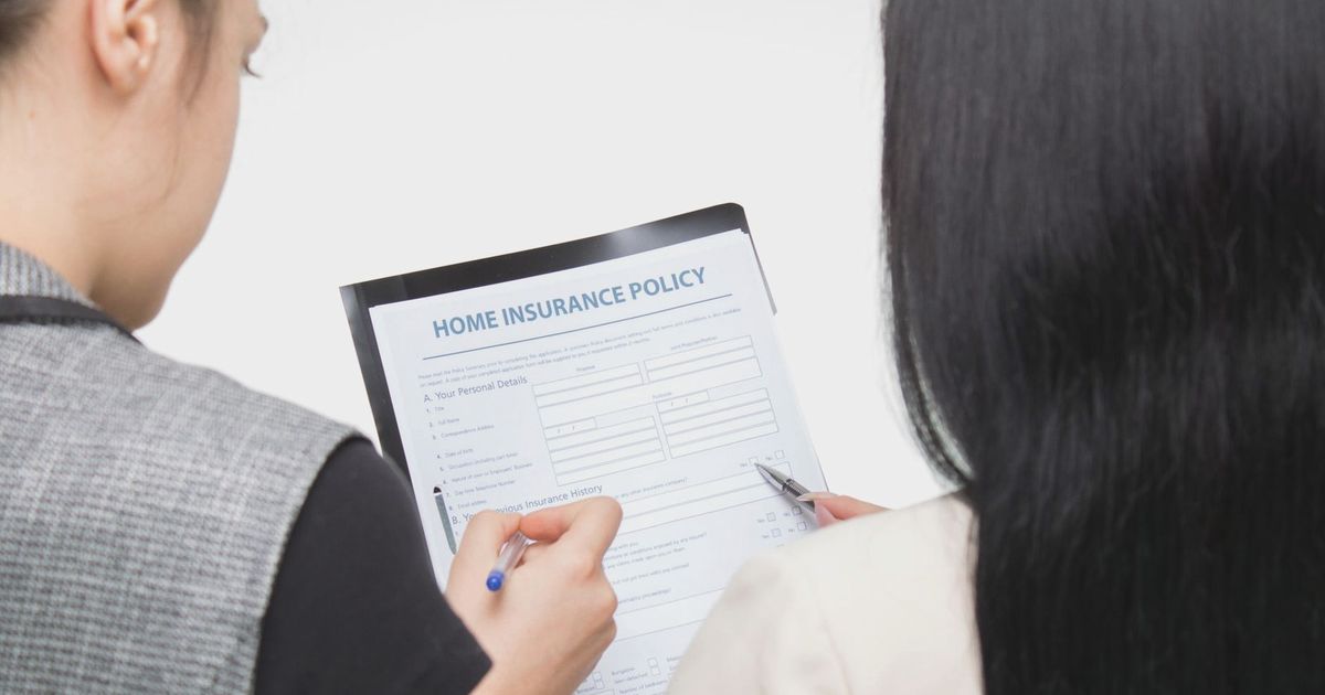 Two women examining home insurance policy form, focused on details.