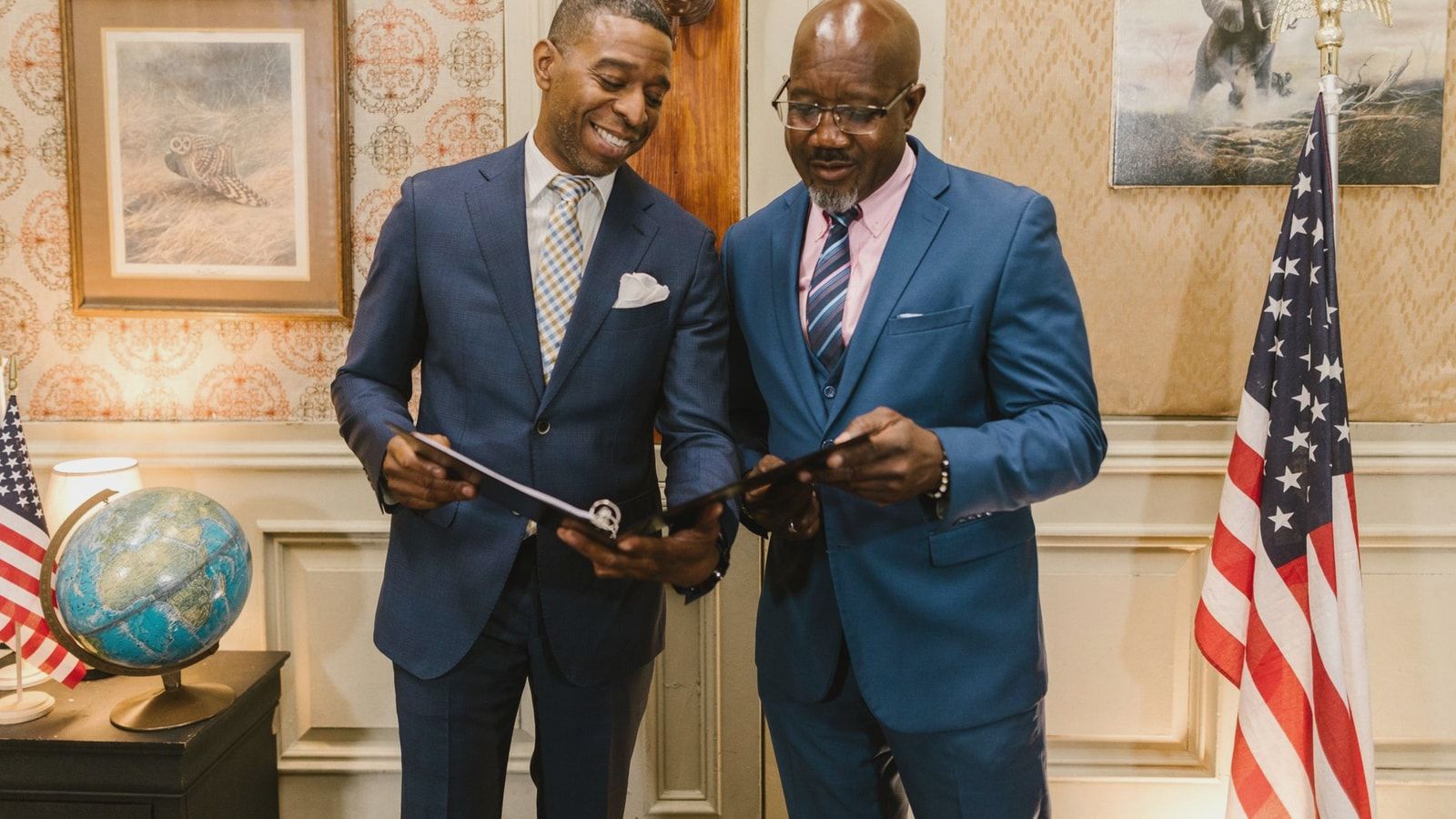 Two male lawyers in corporate suits reviewing documents in an elegantly decorated office setting.