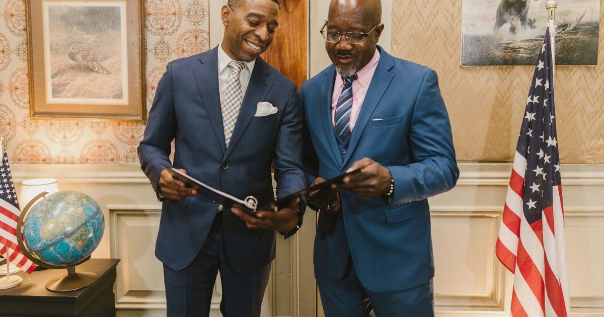 Two male lawyers in corporate suits reviewing documents in an elegantly decorated office setting.