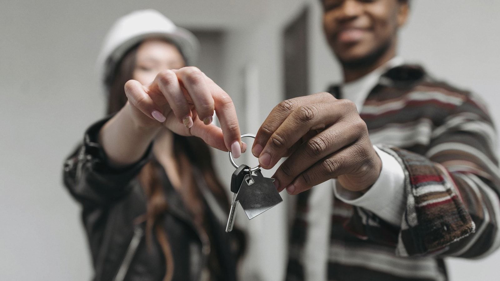 Close-up of a couple joyfully holding keys to their new home, symbolizing new beginnings and home ownership.
