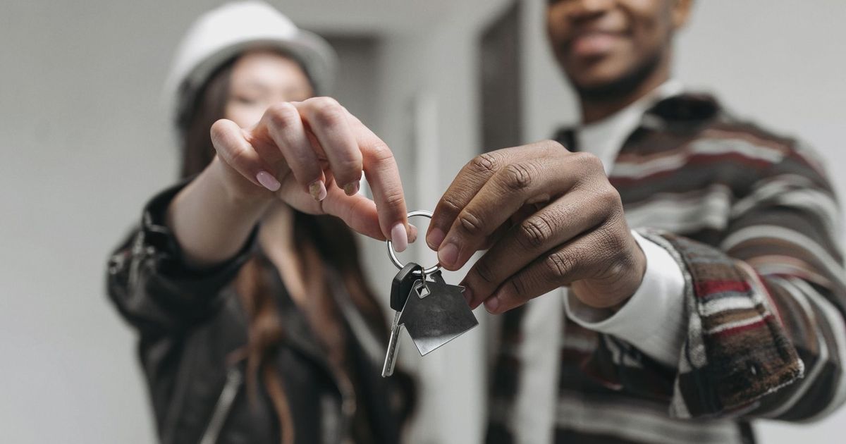 Close-up of a couple joyfully holding keys to their new home, symbolizing new beginnings and home ownership.