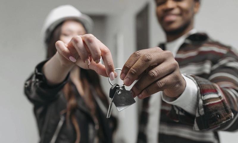 Close-up of a couple joyfully holding keys to their new home, symbolizing new beginnings and home ownership.