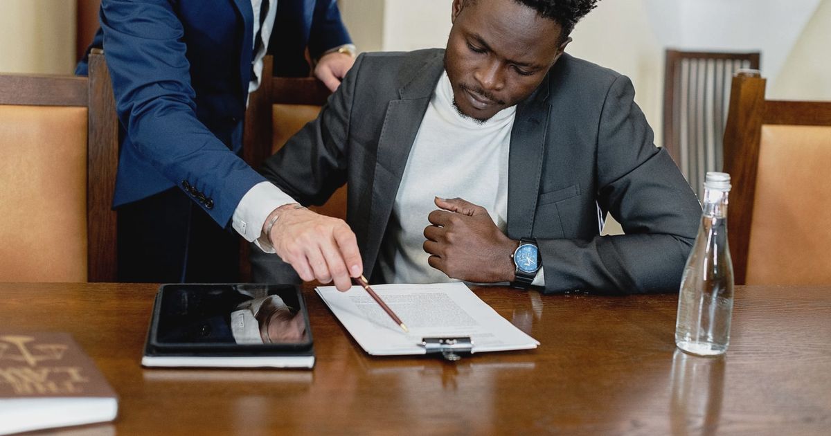 Two businessmen in a legal consultation reviewing a document with a tablet on the desk.