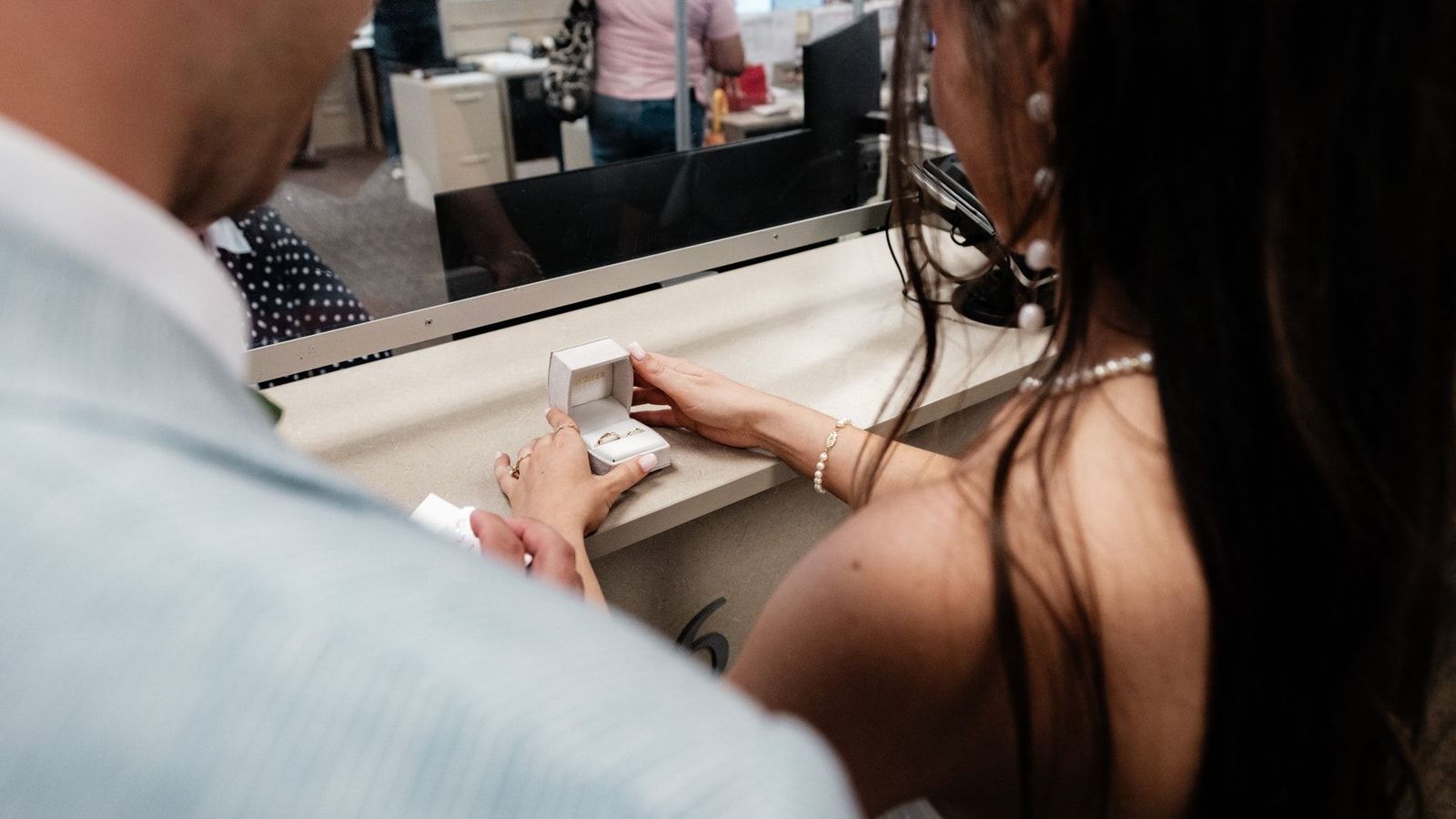 A couple receiving wedding rings at a government office, symbolizing a marriage application.