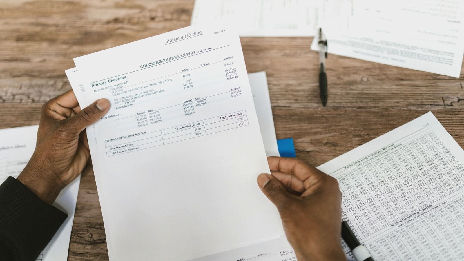 Hands holding financial papers for tax preparation and analysis.