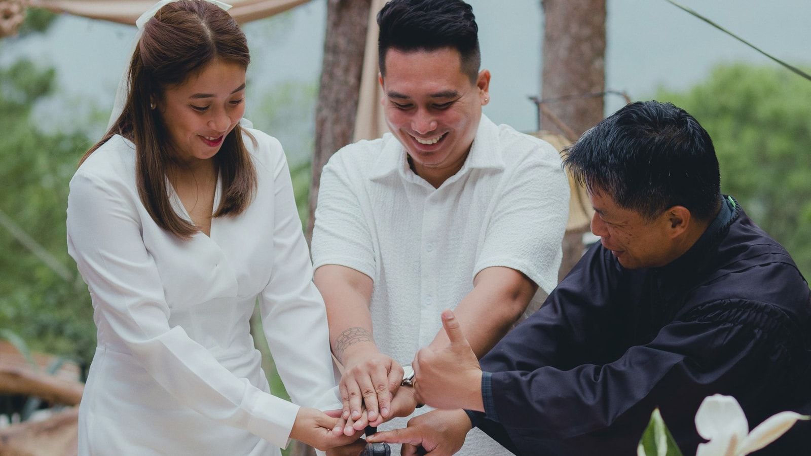 A joyful couple finalizing their wedding with the officiant outdoors.