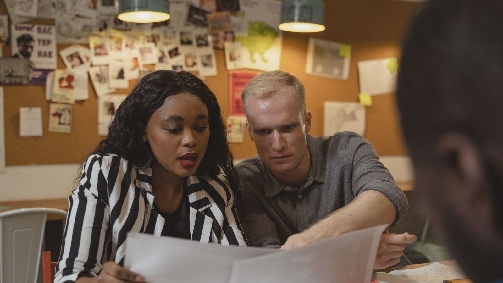 Two colleagues reviewing documents in a creative office setting, working together on a project.