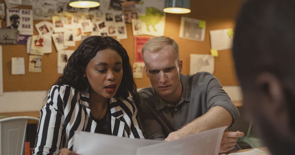 Two colleagues reviewing documents in a creative office setting, working together on a project.