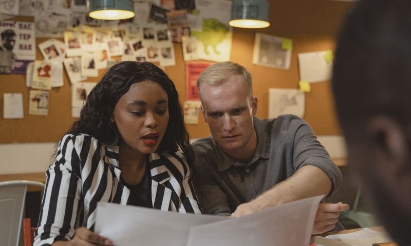 Two colleagues reviewing documents in a creative office setting, working together on a project.