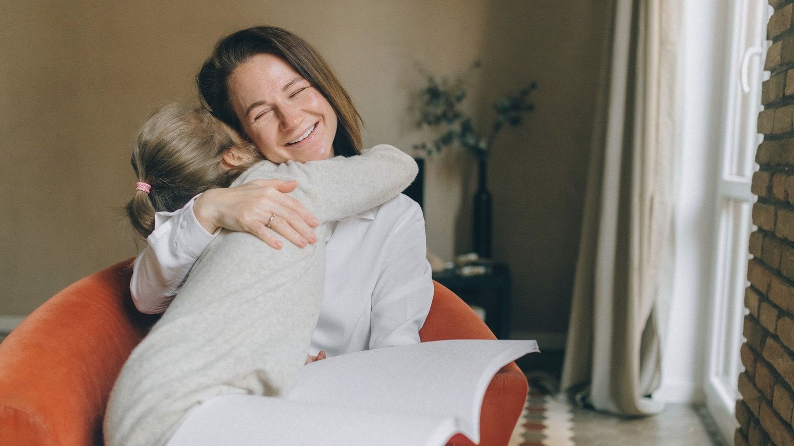 A warm moment between a mother and daughter embracing while reading braille indoors.