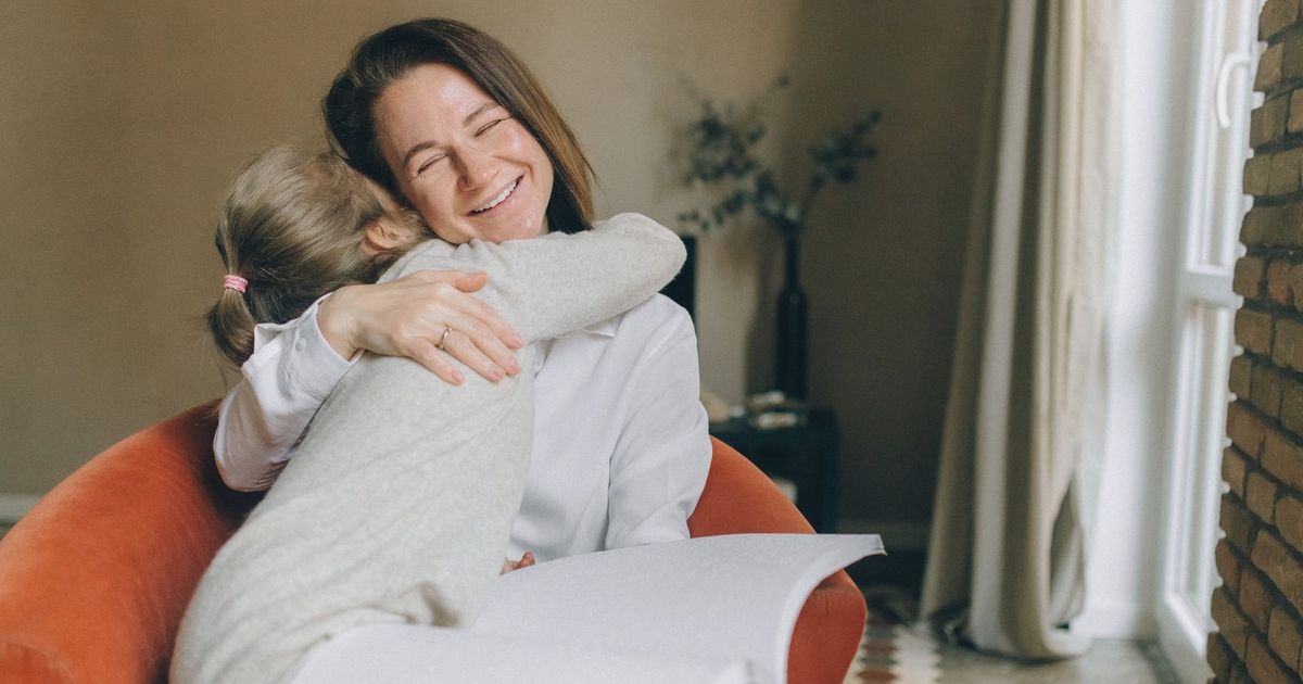 A warm moment between a mother and daughter embracing while reading braille indoors.