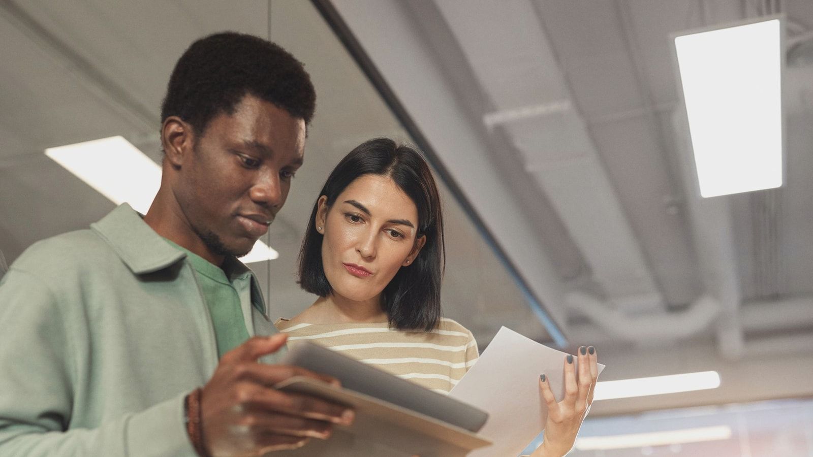 Two professionals collaborating on a project using a digital tablet in a modern office setting.