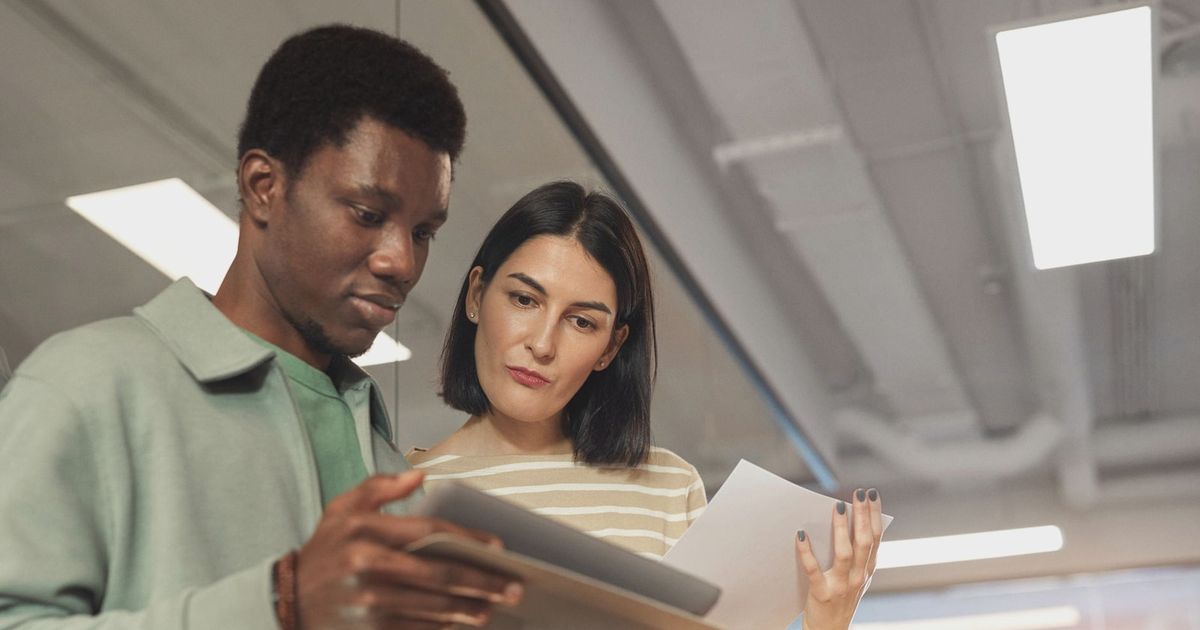 Two professionals collaborating on a project using a digital tablet in a modern office setting.