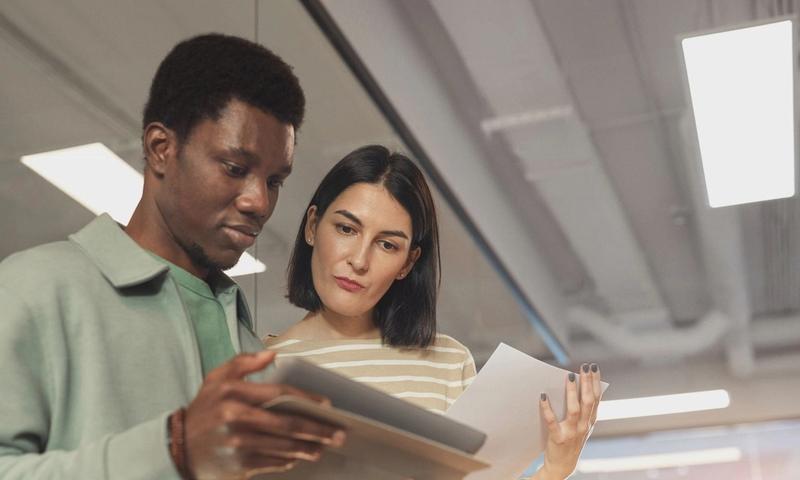 Two professionals collaborating on a project using a digital tablet in a modern office setting.