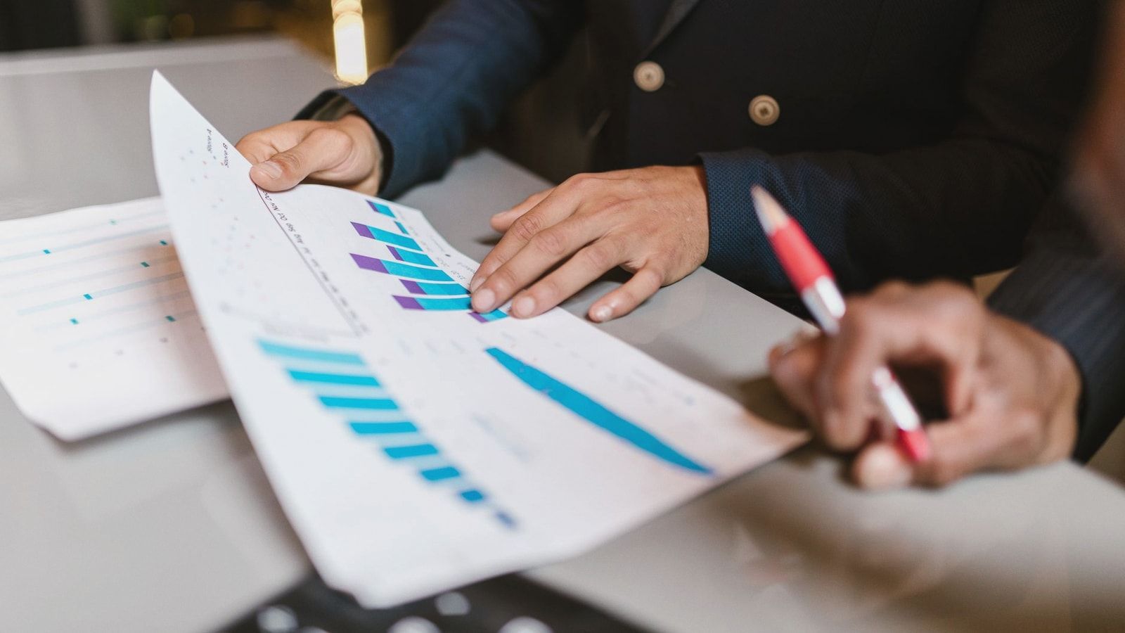 Close-up of professionals reviewing financial graphs at a business meeting.