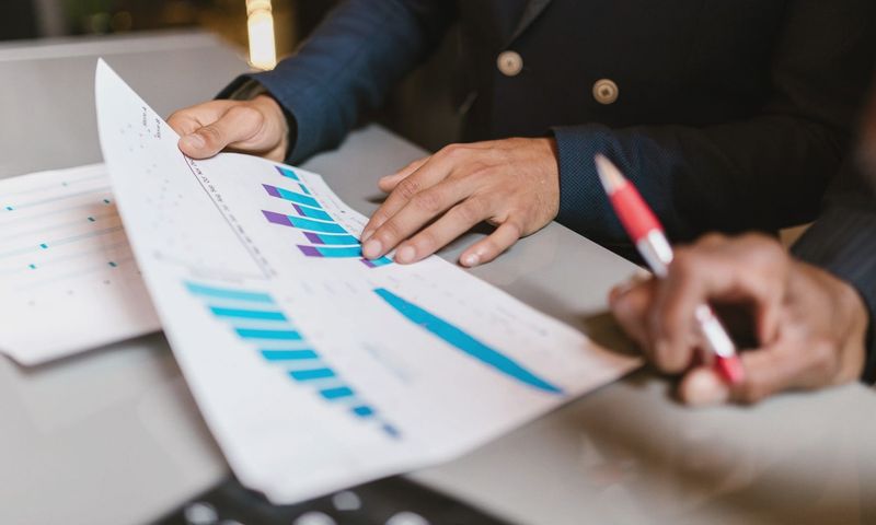 Close-up of professionals reviewing financial graphs at a business meeting.