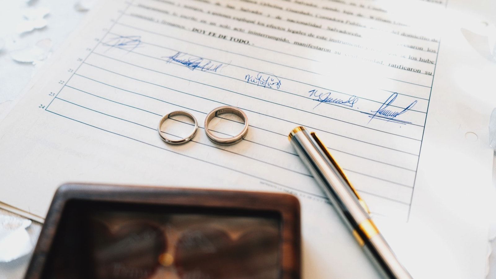 Elegant wedding rings laid on a signed marriage certificate, symbolizing commitment.