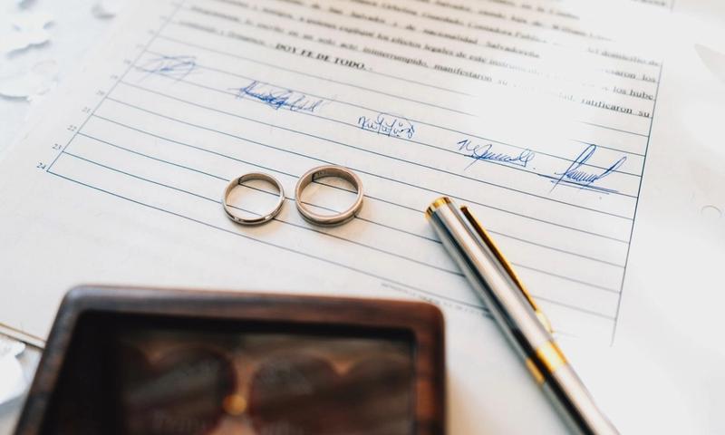 Elegant wedding rings laid on a signed marriage certificate, symbolizing commitment.