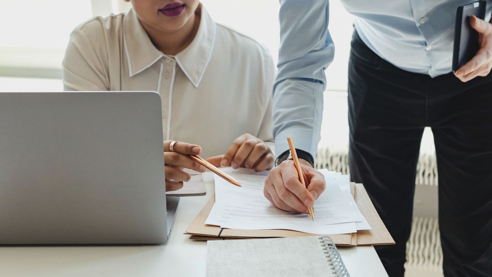 Two colleagues collaborate on paperwork during an office meeting.