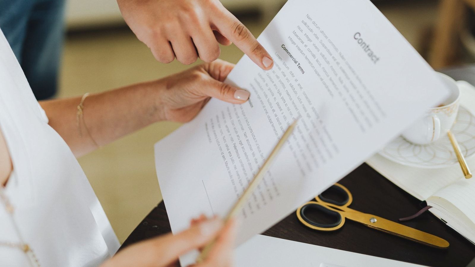 Close-up of two people discussing a business contract at a desk in an office setting.