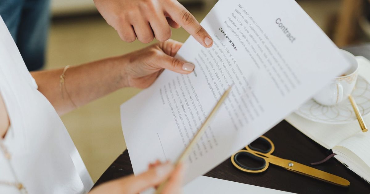 Close-up of two people discussing a business contract at a desk in an office setting.