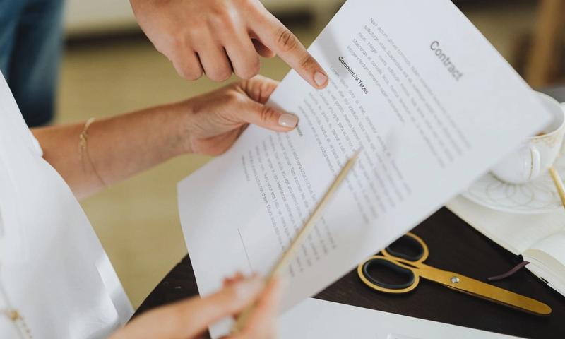 Close-up of two people discussing a business contract at a desk in an office setting.
